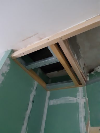 Plafond avec structure en bois partiellement installé, mur vert en arrière-plan.