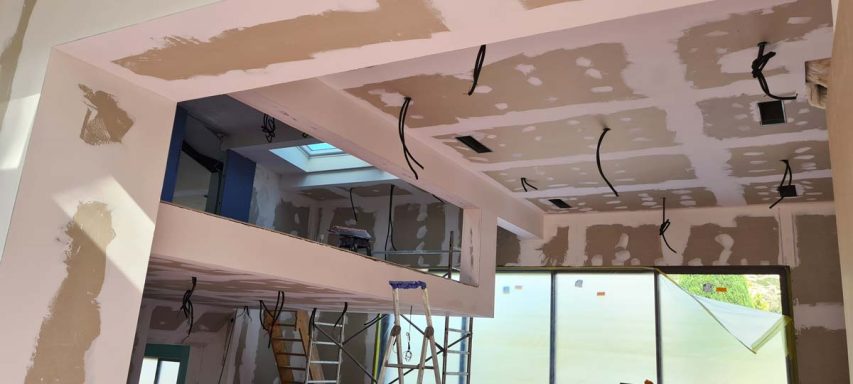 Intérieur d'une maison en rénovation avec câbles exposés et murs non finis.