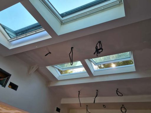 Plafond intérieur avec fenêtres de toit et câbles suspendus.