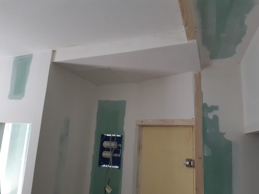 Coin d'une pièce avec des murs en cours de finition et une porte en bois.