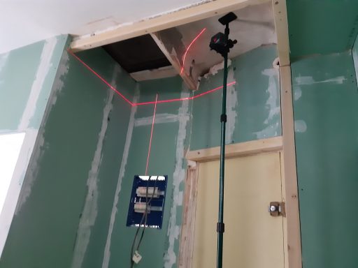 Câblage électrique visible au plafond, avec un panneau de connexion et un trépied.