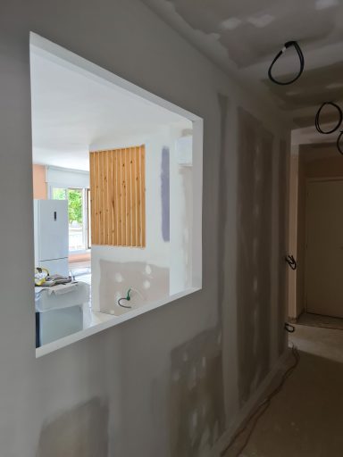 Ouverture rectangulaire sur un mur, donnant sur une cuisine en cours de finition.